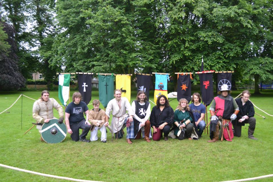 Group picture of contestants. Kneeling, banners overhead.